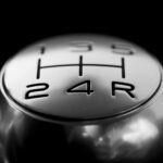 Detailed close-up of a stainless steel gear shift knob against a black background.